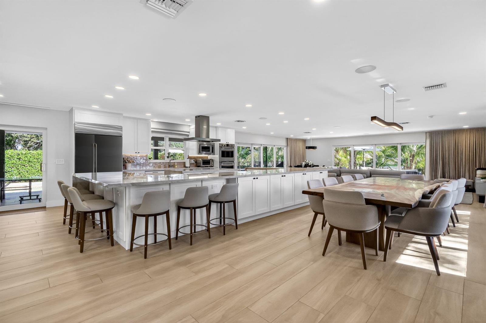 A spacious, modern kitchen features a large island with bar seating and a dining area — 937 SW 34th Court, Boynton Beach FL 33435, BOYNTON BEACH, FL