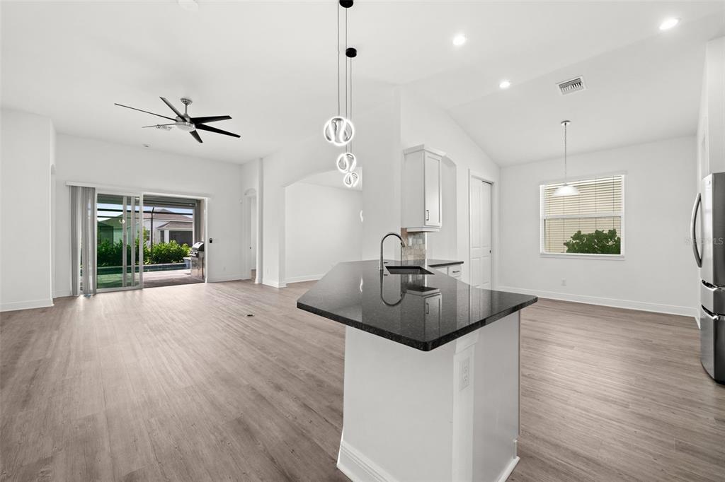 A kitchen with a black granite island, white cabinets, and light wood-look flooring — 15880 ELINA SKY DRIVE, PUNTA GORDA, FL