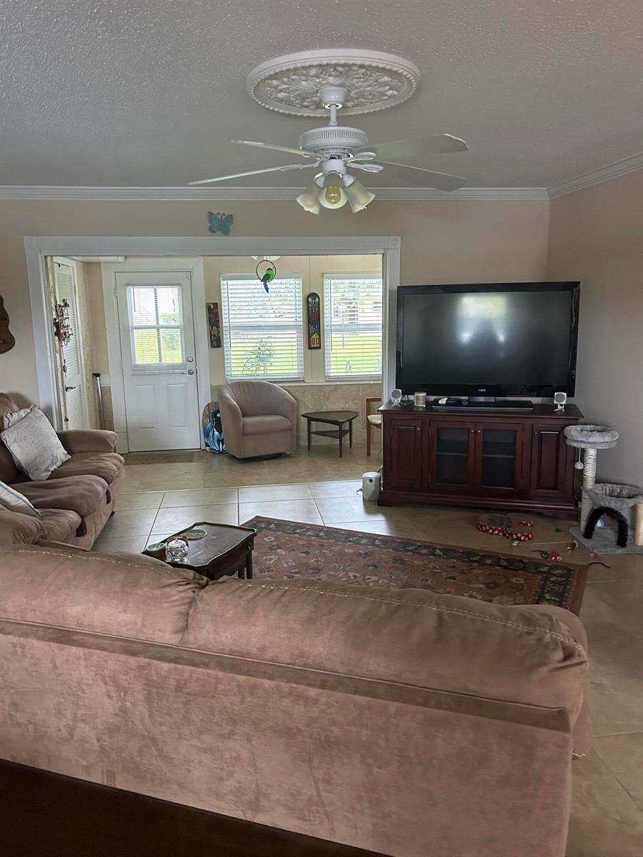 A living room features a brown sectional sofa, a television on a console, and tile flooring — 770 Lori Drive # 245, Palm Springs FL 33461, PALM SPRINGS, FL