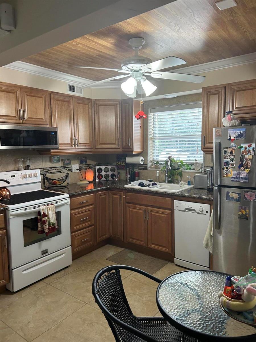 A kitchen features wood cabinets, stainless steel appliances, a ceiling fan, and a wood-look ceiling — 770 Lori Drive # 245, Palm Springs FL 33461, PALM SPRINGS, FL