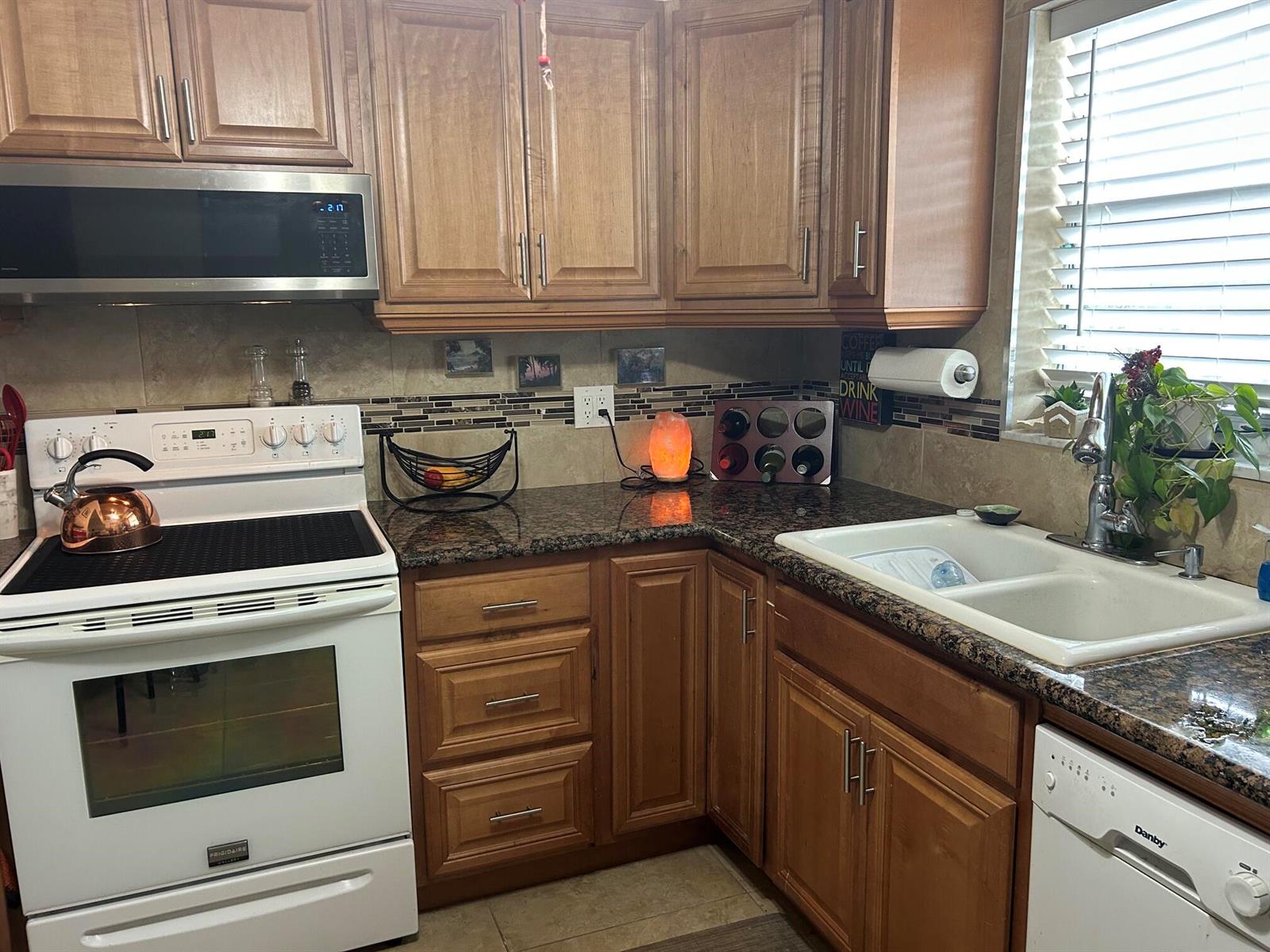 A kitchen features wood cabinets, granite countertops, a white stove, and a double-basin sink — 770 Lori Drive # 245, Palm Springs FL 33461, PALM SPRINGS, FL