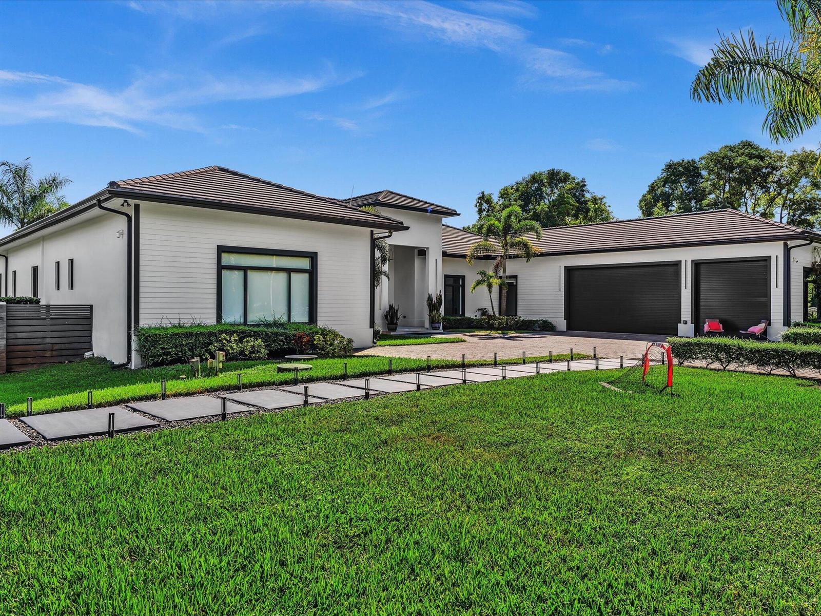 A modern, single-story white house with a dark roof, black trim, and a paved driveway — SOUTHWEST RANCHES, FL