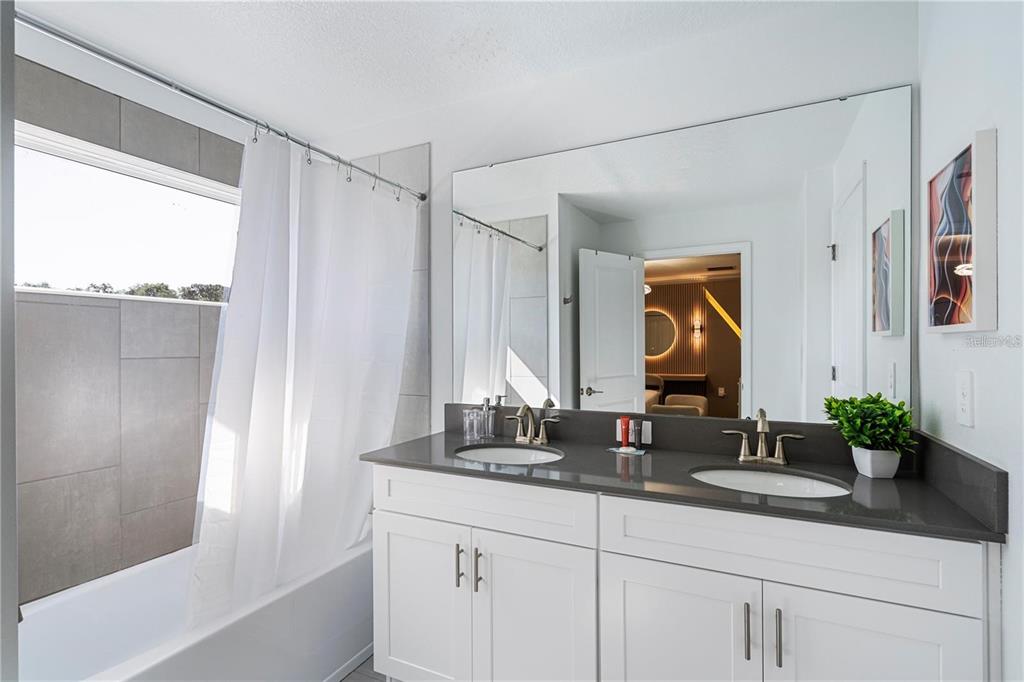 A bathroom features a double vanity with a gray countertop and a shower-tub combination — 2600 READING TRAIL, KISSIMMEE, FL