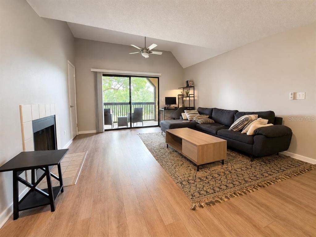 A living room features wood-look flooring, a vaulted ceiling, a fireplace, and a sliding door — 420 FORESTWAY CIRCLE UNIT 307, ALTAMONTE SPRINGS, FL