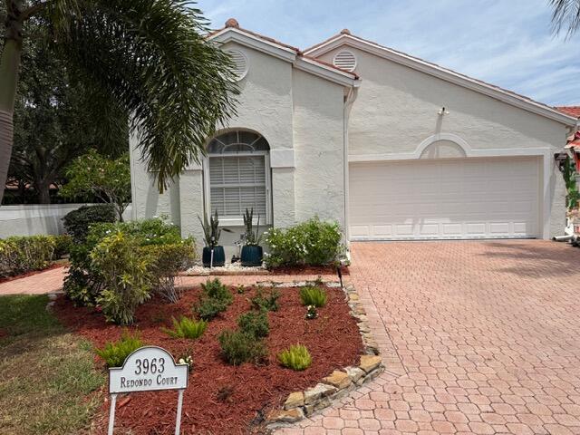 A single-story house with a beige stucco exterior, a two-car garage, and a paved driveway — 3963 Redondo Court, Boca Raton FL 33487, BOCA RATON, FL