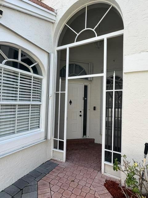 A white front door is framed by a tall arched screen enclosure and brick pavers — 3963 Redondo Court, Boca Raton FL 33487, BOCA RATON, FL