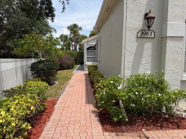 A brick paver walkway leads along the side of a house with light-colored stucco walls — 3963 Redondo Court, Boca Raton FL 33487, BOCA RATON, FL