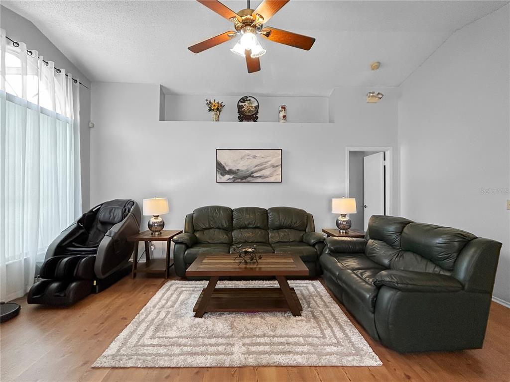 A living room features two dark leather sofas, a massage chair, and a wooden coffee table — 3228 RUNNING BEAR WAY, KISSIMMEE, FL