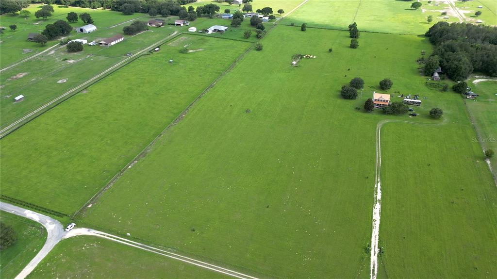 An aerial view shows a large, green pasture with a house and several outbuildings — TBD SE 170TH STREET, WEIRSDALE, FL