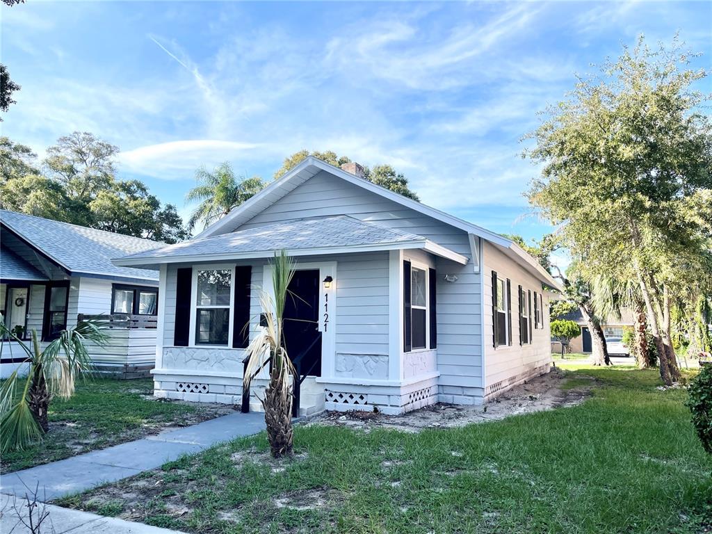 A light gray, single-story house with a front porch and black shutters sits on grass — 1121 10TH AVENUE S, ST PETERSBURG, FL