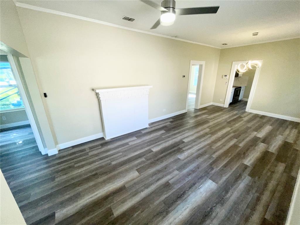 A living room features light-colored walls, a white fireplace, and wood-look flooring — 1121 10TH AVENUE S, ST PETERSBURG, FL