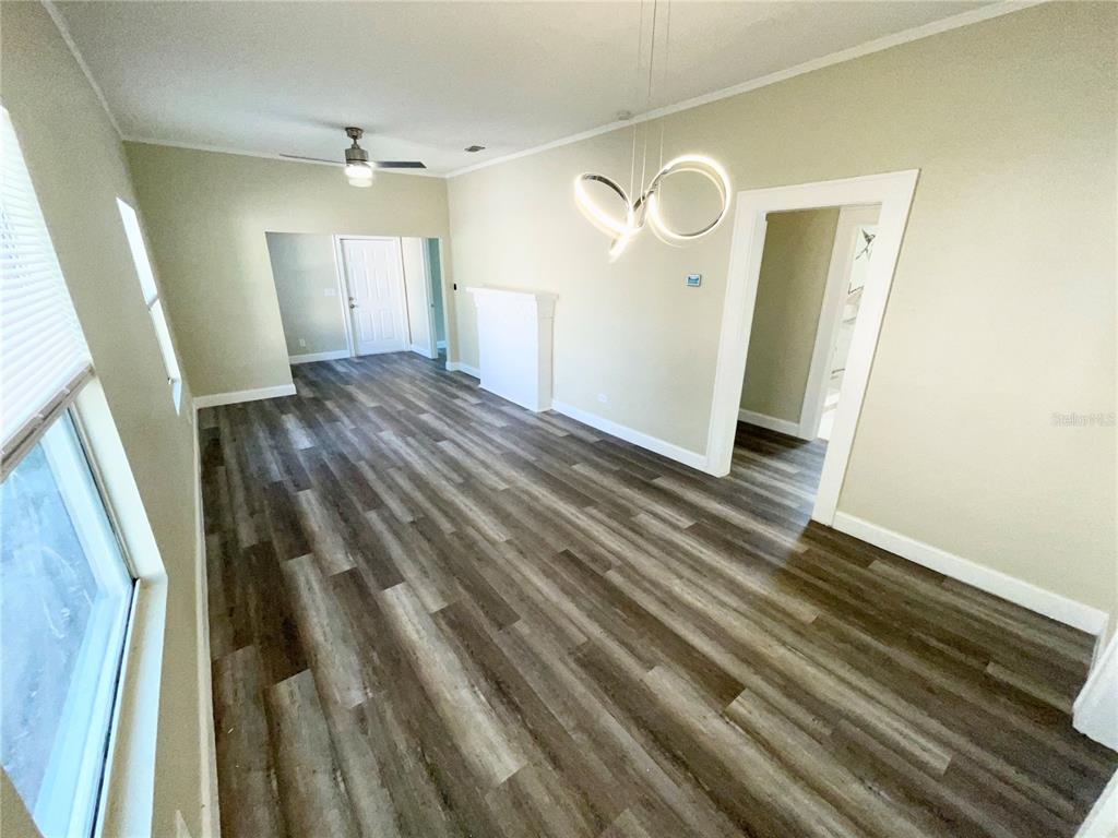 An empty room features wood-look flooring, a modern light fixture, and a white fireplace mantel — 1121 10TH AVENUE S, ST PETERSBURG, FL