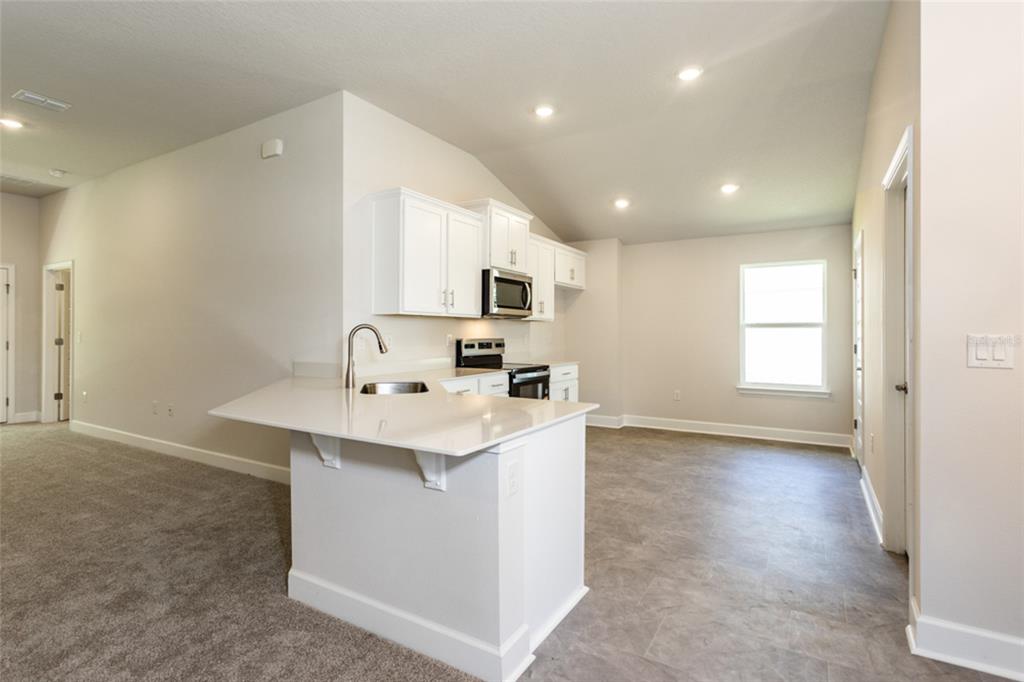 A kitchen with white cabinets, a quartz countertop island, and gray tile flooring — 79 PORT ROYAL DRIVE, PALM COAST, FL