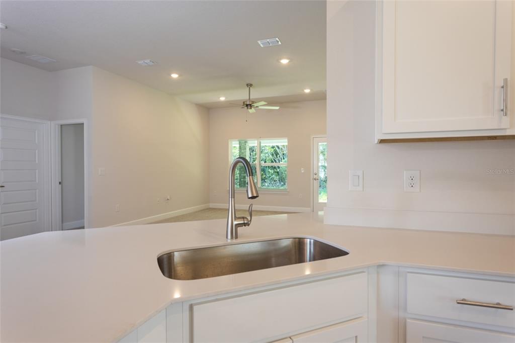 A kitchen sink and faucet are set into a white countertop in a bright kitchen — 79 PORT ROYAL DRIVE, PALM COAST, FL