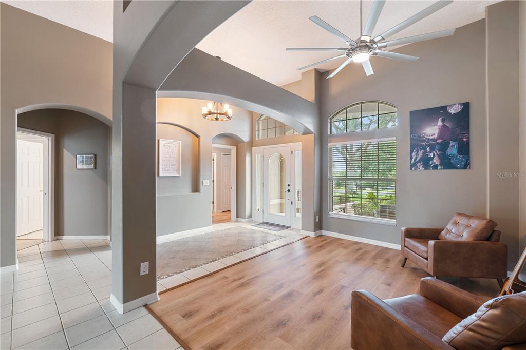 A living room with wood-look flooring, arched entryways, a ceiling fan, and two leather chairs — 1283 LEGENDARY BOULEVARD, CLERMONT, FL