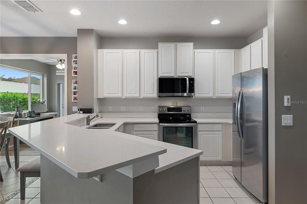 A kitchen with white cabinets, stainless steel appliances, and a white countertop breakfast bar — 1283 LEGENDARY BOULEVARD, CLERMONT, FL