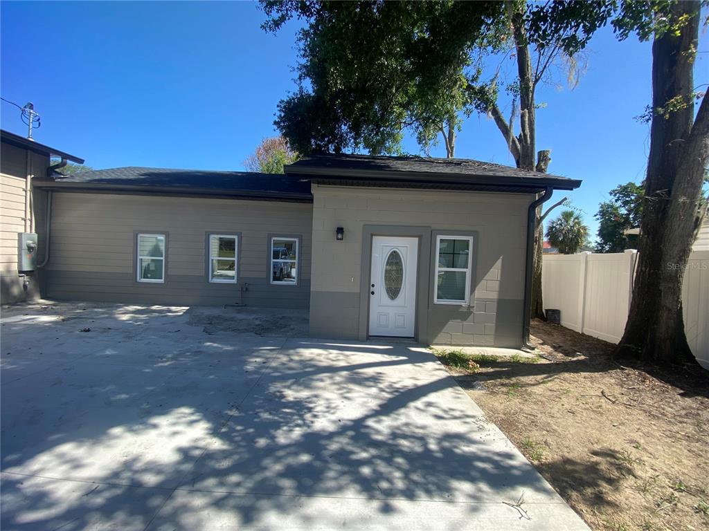 A single-story house exterior features a white front door, gray siding, and a concrete driveway — 207 AVENUE E SE, WINTER HAVEN, FL