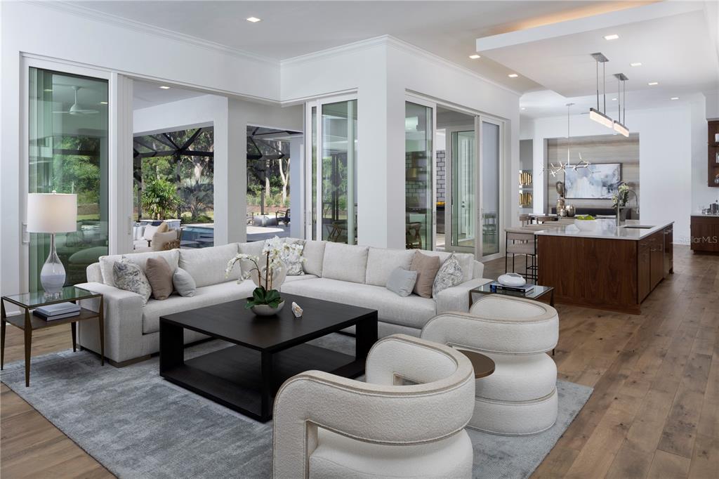 A modern open-concept living room features a sectional sofa, two armchairs, and a kitchen island — 12364 SW 16TH LANE, NEWBERRY, FL