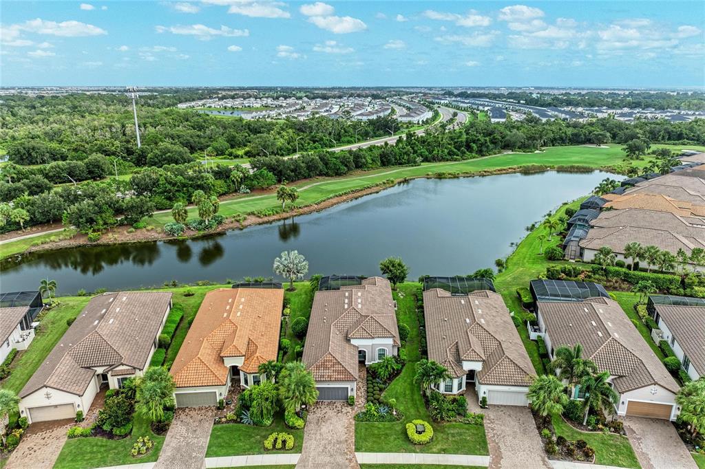 An aerial view shows a row of suburban houses with tiled roofs overlooking a lake — 13321 SORRENTO WAY, BRADENTON, FL