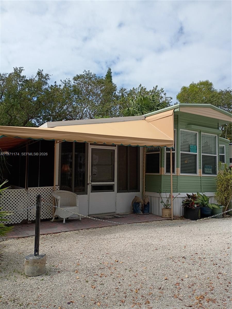 A mobile home with a green exterior, a tan awning, and a screened-in porch area — 101551 Overseas Hwy, 147, Key Largo FL 33037, KEY LARGO, FL