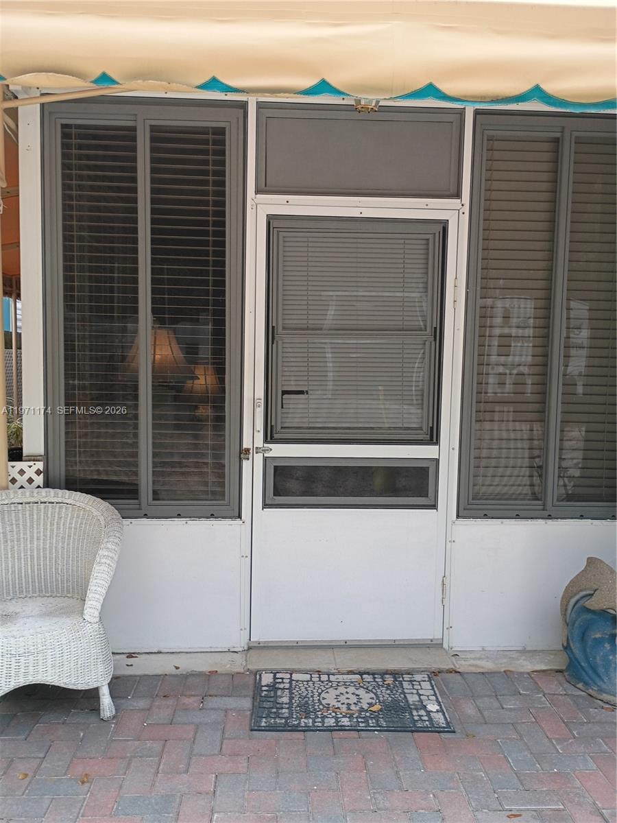 A white screen door is flanked by two large windows on a paved patio area — 101551 Overseas Hwy, 147, Key Largo FL 33037, KEY LARGO, FL
