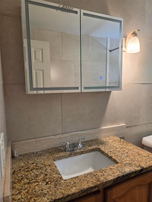 A bathroom vanity features a granite countertop, an undermount sink, and a lighted medicine cabinet — 6100 WYOMING AVENUE, NEW PORT RICHEY, FL