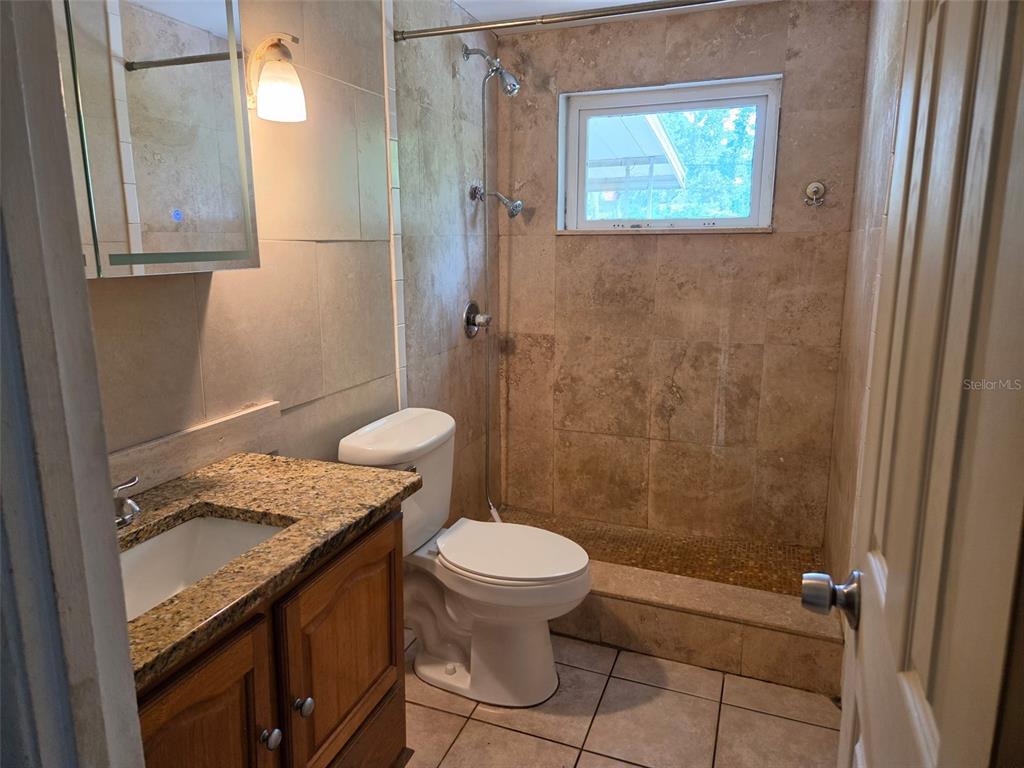 A bathroom with a granite-topped vanity, a toilet, and a tiled walk-in shower — 6100 WYOMING AVENUE, NEW PORT RICHEY, FL