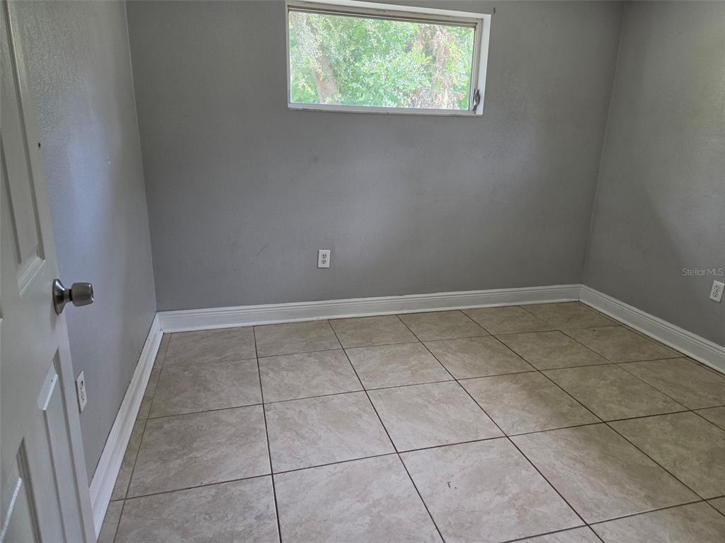An empty room features gray walls, light-colored tile flooring, and a single rectangular window — 6100 WYOMING AVENUE, NEW PORT RICHEY, FL