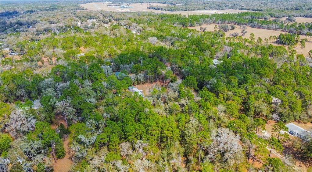 An aerial view shows a house nestled within a dense, wooded forest near an airfield — 5500 S CHEROKEE TERRACE, INVERNESS, FL