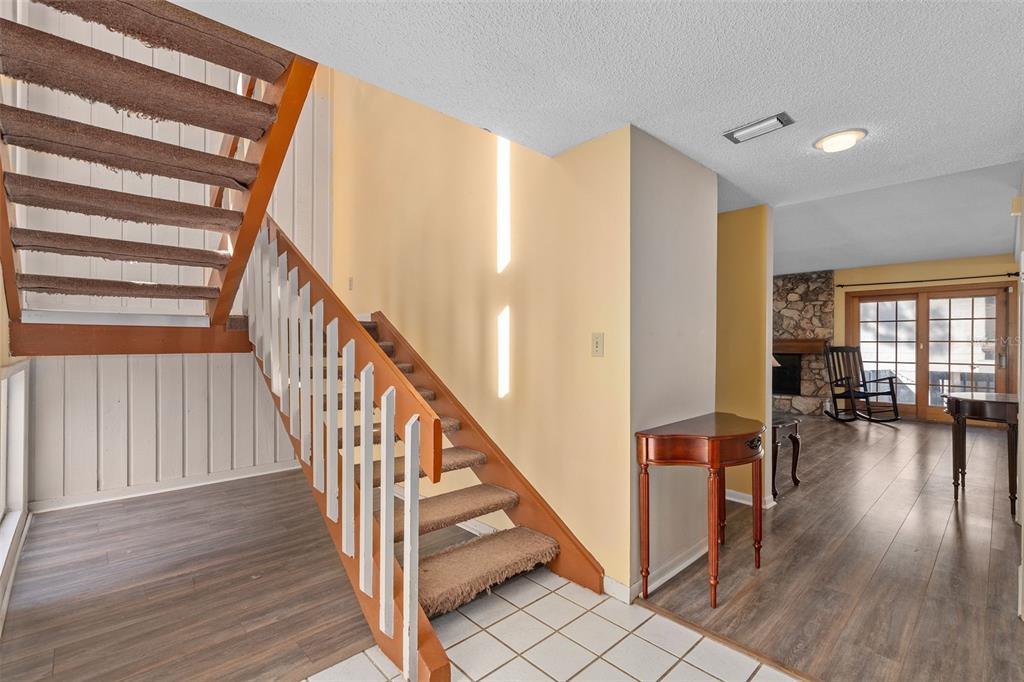 An entryway features a carpeted staircase with white railings, tile flooring, and a wood-floored living area — 114 HIDDEN OAK DRIVE, LONGWOOD, FL