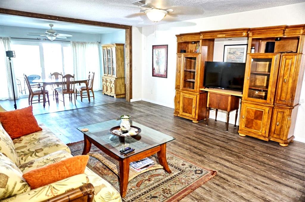 A living room with wood-look flooring, a glass coffee table, and a large wooden entertainment center — 1873 MAZO MANOR UNIT T9, LUTZ, FL