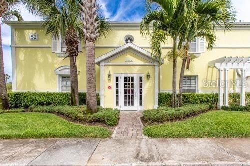 A two-story yellow building features a central white-framed entrance, palm trees, and a sidewalk — 4714 COBIA DRIVE SE UNIT D, ST PETERSBURG, FL