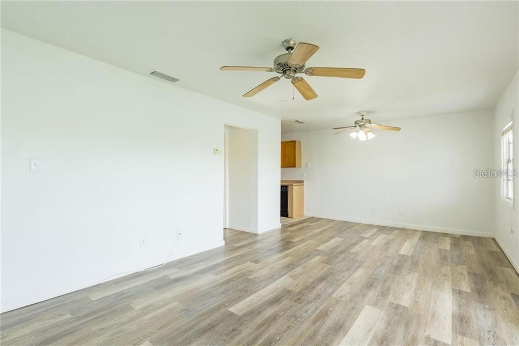 A living room with white walls, wood-look flooring, and two ceiling fans — 4714 COBIA DRIVE SE UNIT D, ST PETERSBURG, FL