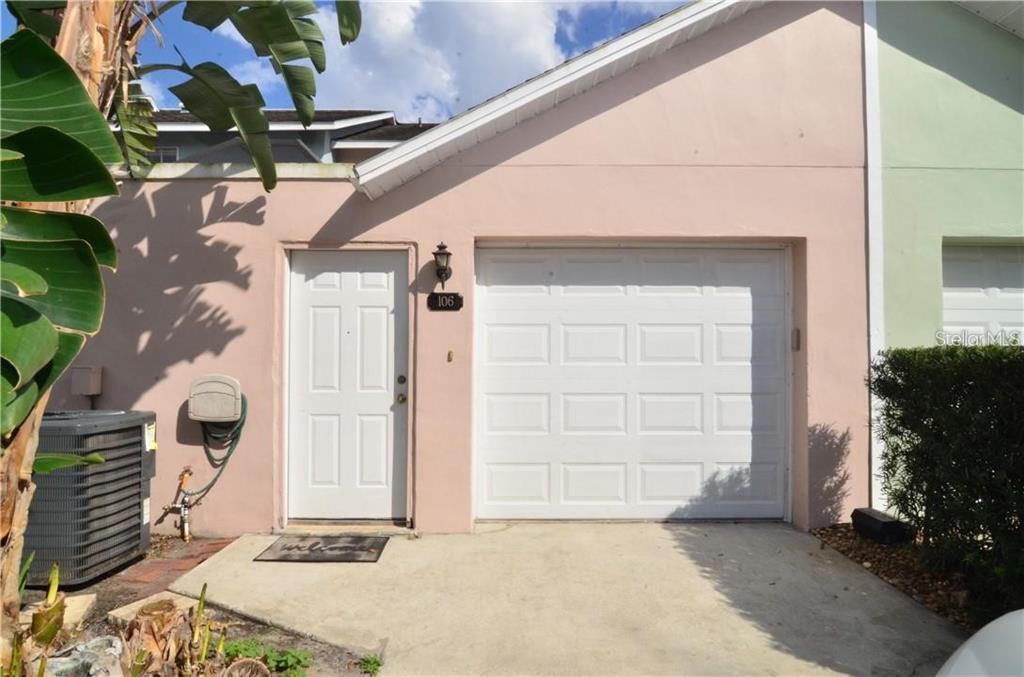A two-story townhouse exterior features a dark front door, a concrete walkway, and manicured hedges — 106 S PRIMROSE DRIVE, ORLANDO, FL