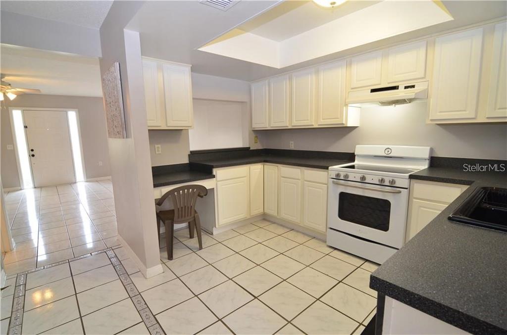 A kitchen features white cabinets, black countertops, a white stove, and a white refrigerator — 106 S PRIMROSE DRIVE, ORLANDO, FL