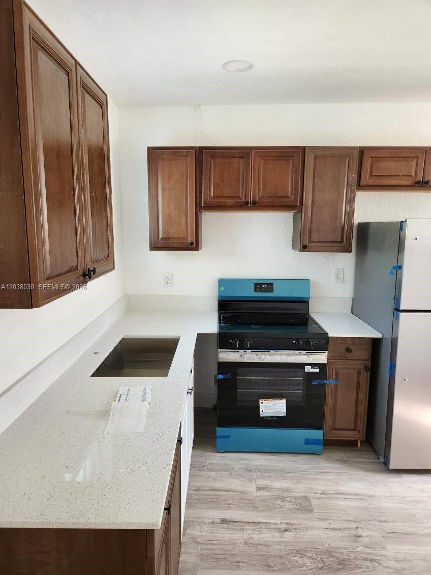 A bright room features light wood-look flooring, white walls, a door, and large windows — 2501 NW 55th Ter, Miami FL 33142, MIAMI, FL
