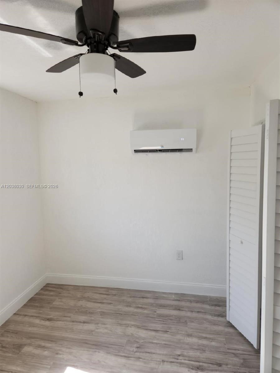 A room with wood-look flooring transitions to a white marble-tiled living area — 2501 NW 55th Ter, Miami FL 33142, MIAMI, FL