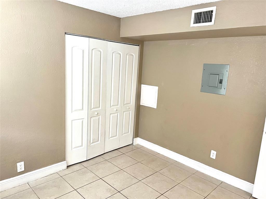A room with beige walls, tiled flooring, a white bi-fold closet, and an electrical panel — 4425 Treehouse Lane # A, Tamarac FL 33319, TAMARAC, FL