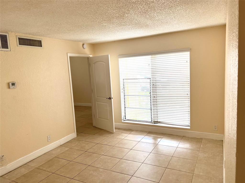 An empty room with beige walls, tile flooring, a white door, and a window with blinds — 4425 Treehouse Lane # A, Tamarac FL 33319, TAMARAC, FL