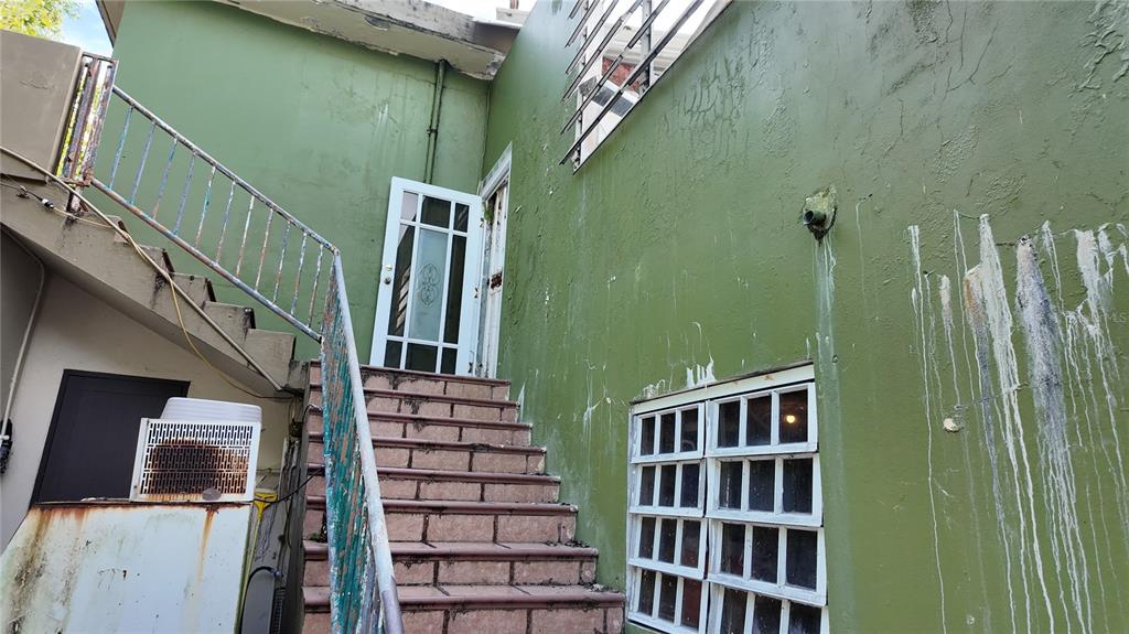 An exterior view of a green building with a staircase leading to a white door — 690 LOS NABORIAS STREET, VEGA ALTA, PR