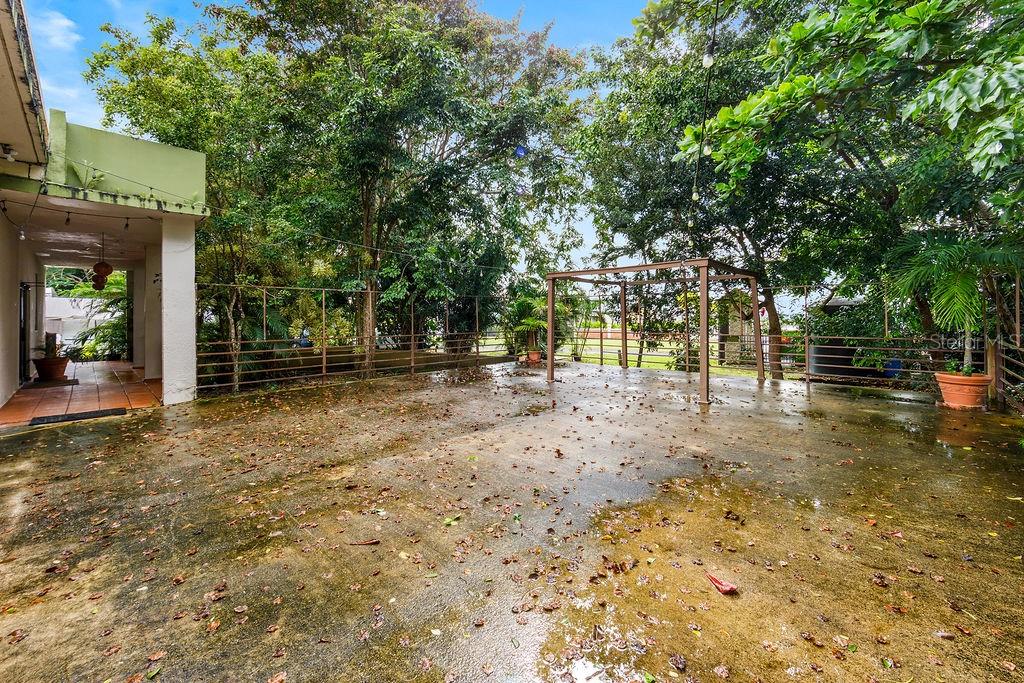 A concrete patio features a metal pergola, a covered porch, and surrounding trees — 690 LOS NABORIAS STREET, VEGA ALTA, PR