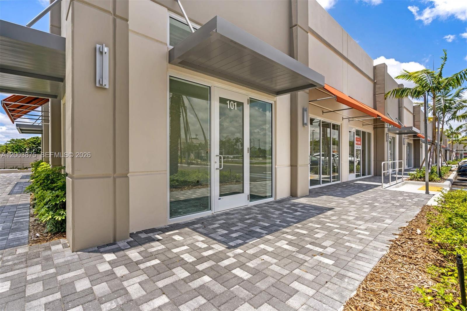 The exterior of a commercial building features glass storefronts, gray awnings, and paved walkways — 9620 Stirling Rd # 101, Cooper City FL 33024, COOPER CITY, FL