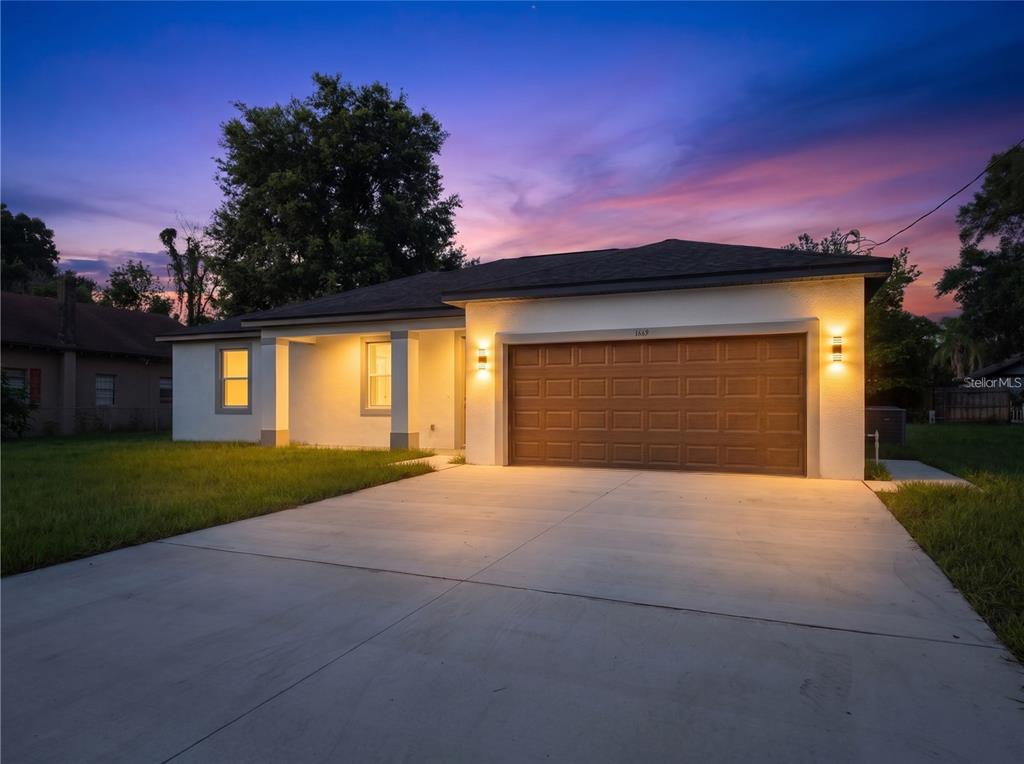 A single-story house with a brown garage door and a concrete driveway at dusk — 1449 KATHLEEN ROAD, LAKELAND, FL