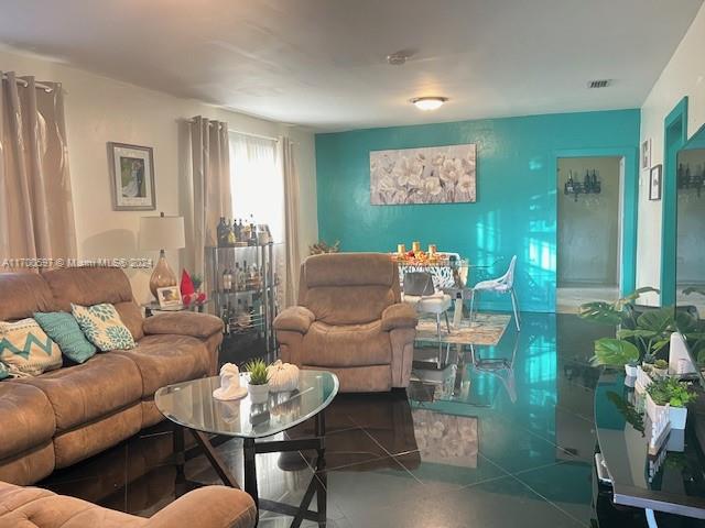 A living room features brown furniture, a glass coffee table, and a bright turquoise accent wall — 161 NW 35th St, Miami FL 33127, MIAMI, FL