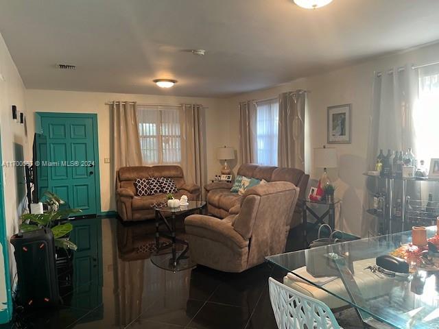 A living room features a teal door, brown furniture, and glossy black tile flooring — 161 NW 35th St, Miami FL 33127, MIAMI, FL