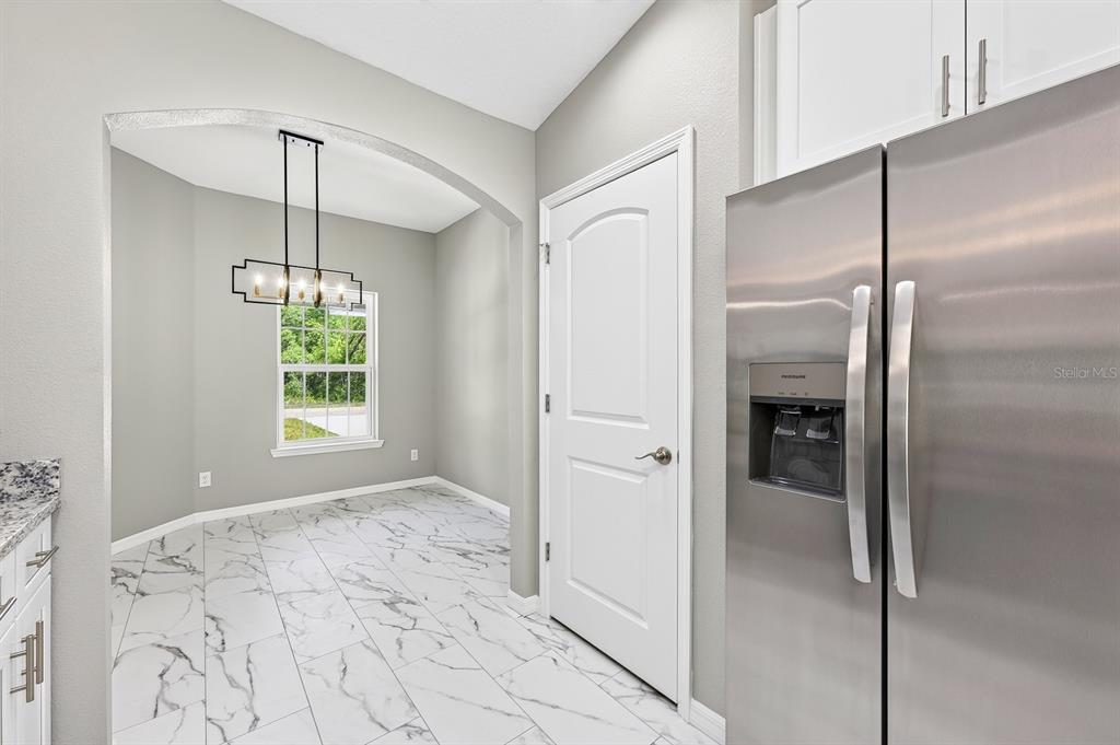 A kitchen with a stainless steel refrigerator leads into a dining area with tiled floors — 36 FISHER LANE COURSE, OCKLAWAHA, FL