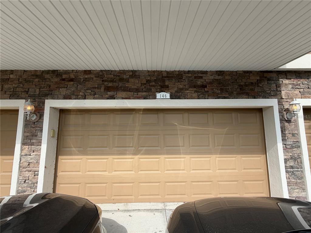 A tan garage door with the number 146 is framed by stone veneer and a white soffit — 7001 INTERBAY BOULEVARD UNIT 146, TAMPA, FL