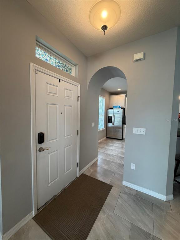 An entryway with a white door, arched opening to a kitchen, and light-colored tile flooring — 7001 INTERBAY BOULEVARD UNIT 146, TAMPA, FL
