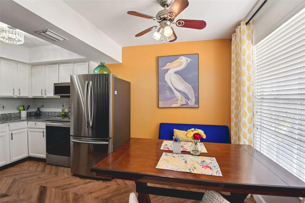 A kitchen and dining area with white cabinets, stainless steel appliances, and a blue bench — 14019 NOTREVILLE WAY, TAMPA, FL