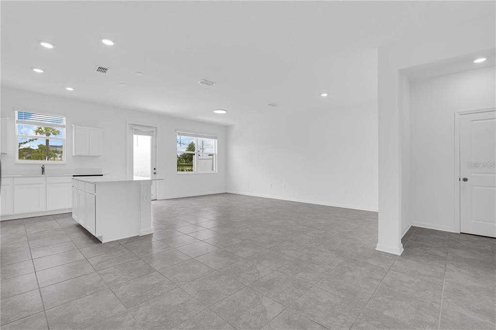 An open-concept kitchen and living area features white cabinetry, a center island, and tile flooring — 294 BOGEY DRIVE, DAVENPORT, FL